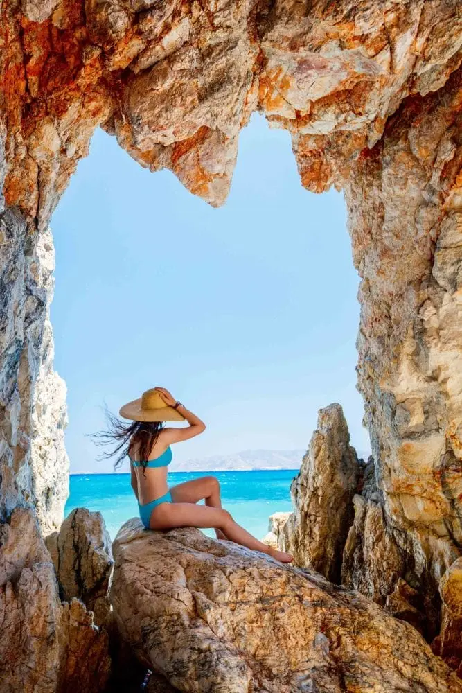 Cute girl enjoying breathtaking beach dotted with amazing sea caves on Greek island of Milos